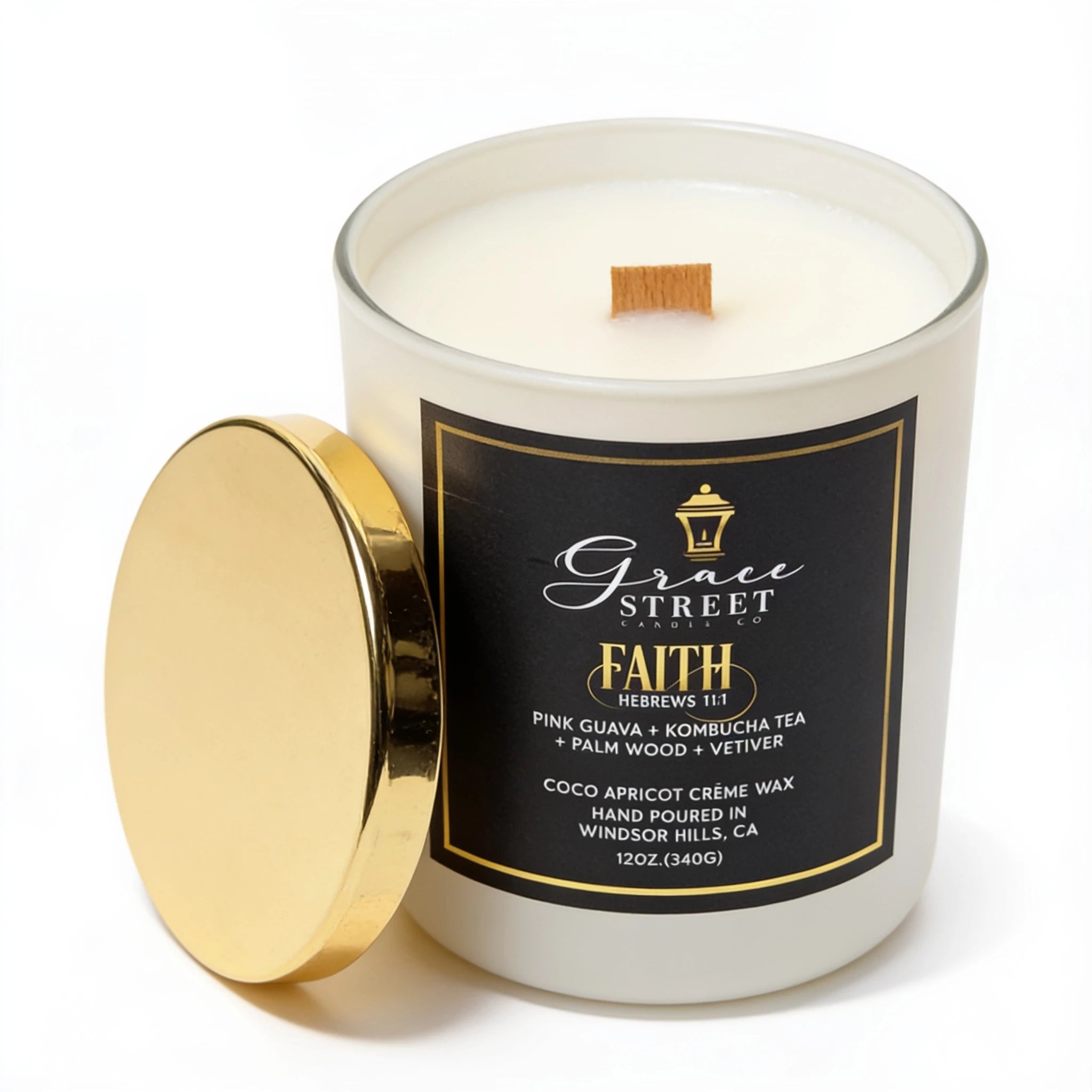 A 12 oz glass jar candle with white wax and a wooden wick, shown with its gold lid leaning against the front. The label is black with gold text reading 'Grace Street Candle' and 'FAITH'.